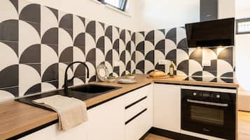 Una cocina moderna con salpicadero de azulejos blanco y negro, horno empotrado y encimera de madera.