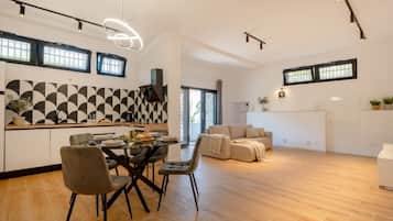 Una cocina moderna con salpicadero geométrico, un comedor con mesa de vidrio y una sala de estar con sofá.