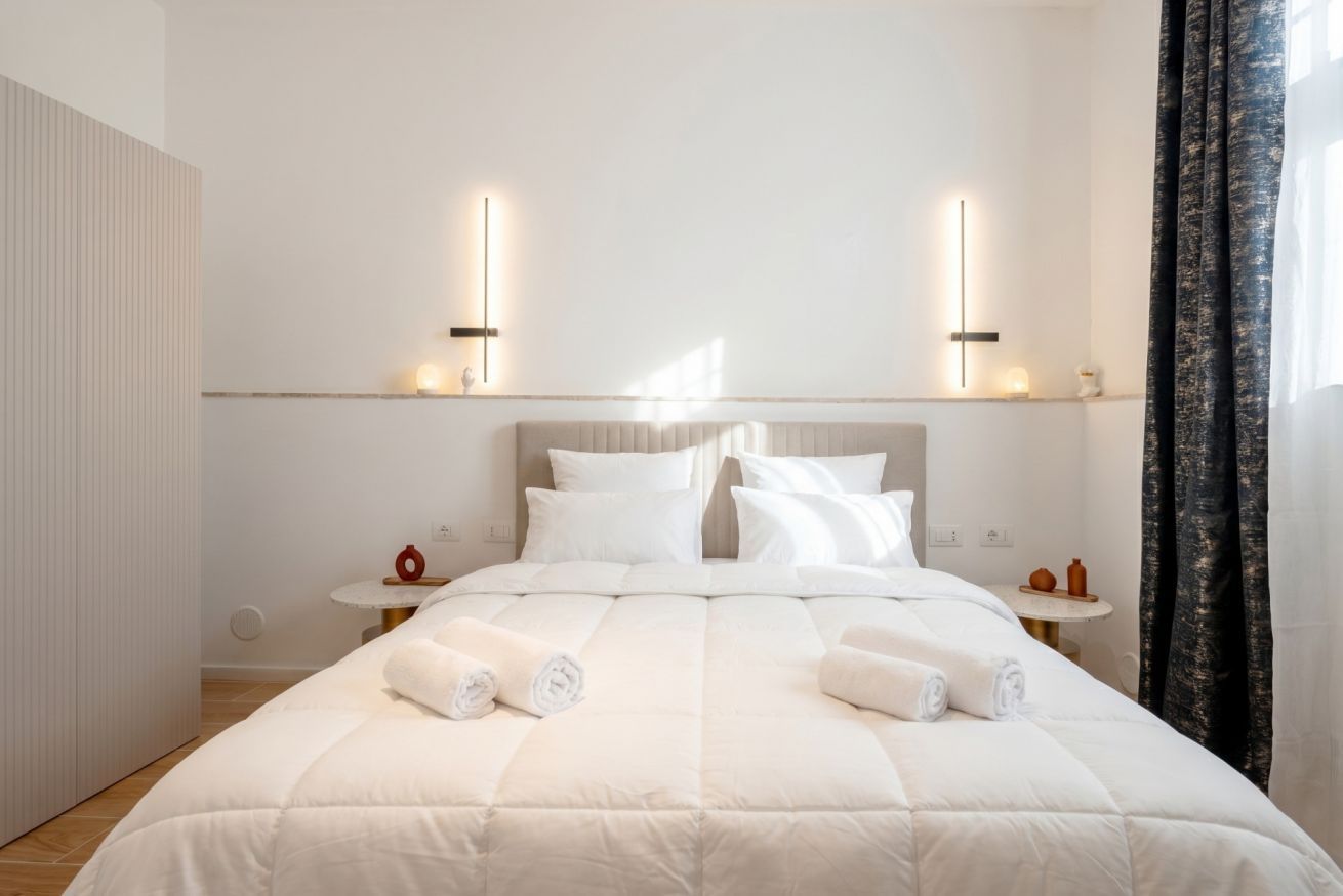 Una habitación de hotel moderna con una cama grande, dos mesitas de noche y una pequeña mesa redonda.