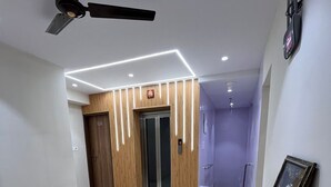 Een moderne hotel lobby met een houten receptiebalie, een plafondventilator en een aan de muur bevestigd telefoon.