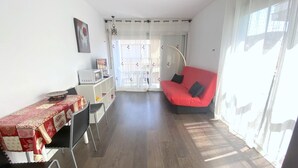 A compact living space with a dining area, a sofa, and a small kitchen area. - Cozy studio in Roses with air conditioning and terrace (Roses)