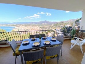 A balcony with a table set for four, overlooking a scenic landscape with mountains and a body of water. - Beautiful apartment with terrace and private parking in Roses (Roses)