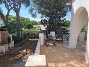 A patio area with a stone fireplace, outdoor seating, and a view of a hillside. - Welcoming house in L'Escala, 1500m from the beach, perfect for families (L'Escala)