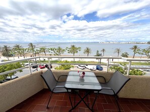 A balcony with a table and chairs overlooking a beach and the sea. - Renovated beachfront apartment with AC and balcony in Roses (Roses)