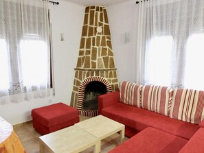A living room with a stone fireplace, red sofa, and a small table.