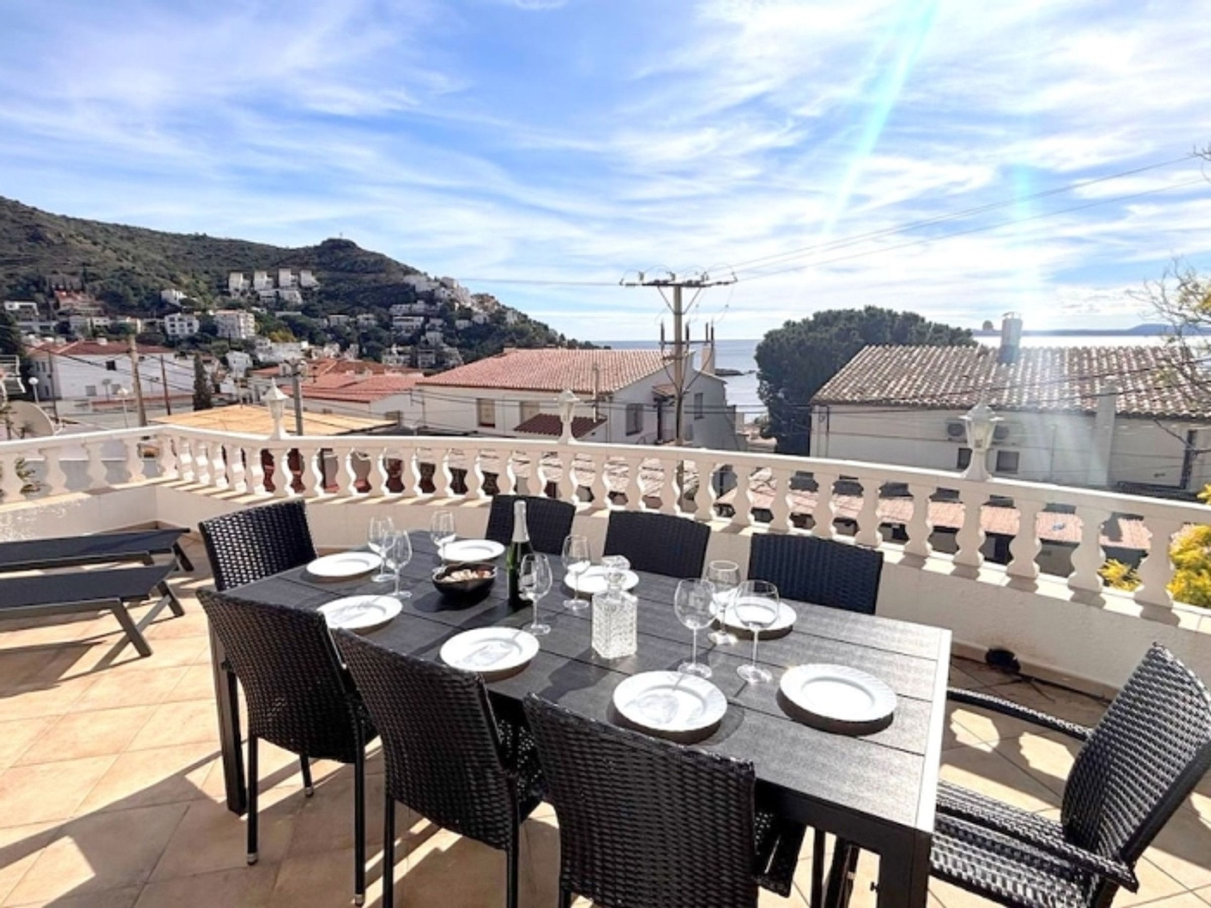 Une terrasse avec une table dressée pour le dîner, offrant une vue sur une ville côtière.