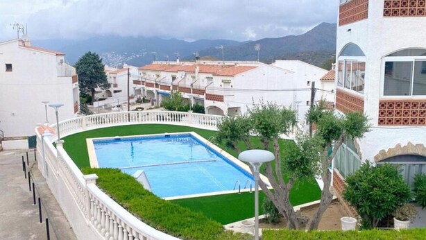 A swimming pool surrounded by a white balustrade, with a view of residential buildings and mountains in the background. - Charming House in Roses: Private Terrace, Pool, A/C, Parking, Sleeps 4 (Roses)