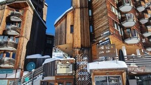 Un edificio de madera con varios balcones y carteles que indican diferentes servicios, como un bar y un restaurante.