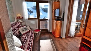 Ein gemütliches Wohnzimmer mit einer Couch, einem kleinen Tisch und einem Fernseher.