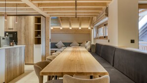 Eine moderne Küche mit Holzbalken, einem langen Holztisch und einer integrierten Bank.