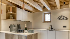 Eine moderne Küche mit Holzbalken, einer zentralen Kochinsel und einem Wandgemälde mit Bergmotiven.