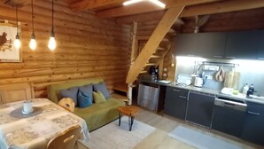 En mysig stuga med träpanel på insidan, med ett matområde, en soffa och ett kök.
