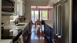 La cuisine est équipée d’un réfrigérateur en acier inoxydable, d’un four à micro-ondes et d’une cuisinière. On y trouve également un coin repas avec une table et des chaises.
