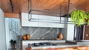 Una cocina moderna con techo de madera, salpicadero de mármol y una isla central con taburetes de bar.