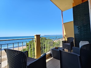 A balcony with outdoor furniture, a view of the sea, and a brick wall.