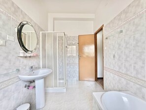 A modern bathroom with a sink, mirror, shower, and toilet.