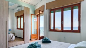 Ein Hotelzimmer mit Bett, Spiegel, Fenster mit Aussicht und einer Tür zum Balkon.