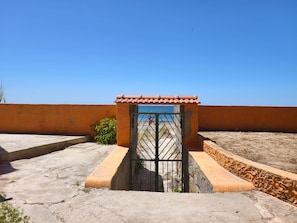 Eine Dachterrasse mit einem Metallgitter, einer Ziegeldachkonstruktion und einem strahlend blauen Himmel.