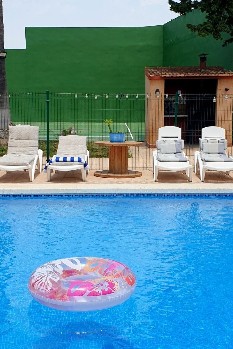 A swimming pool with lounge chairs and a small table.