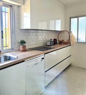 Eine moderne Küche mit weißen Schränken, einem Geschirrspüler, einem Toaster und einer Topfpflanze.