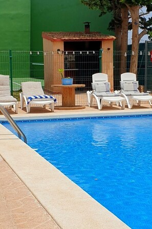 Ein Schwimmbecken mit Liegestühlen und einer kleinen Holzkonstruktion.