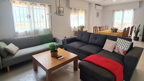Una sala de estar con dos sofás, una mesa de centro y un comedor al fondo.