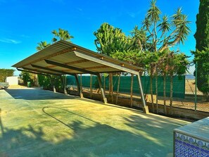 A covered outdoor area with a concrete floor, surrounded by trees and a fence. - Villa La Yuca: private pool, outdoor barbecue, and private parking (pet-friendly) (Los Alcázares)