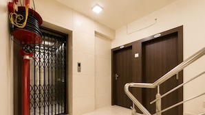 Pasillo de hotel con extintor rojo, una reja metálica y una escalera con barandilla de metal.
