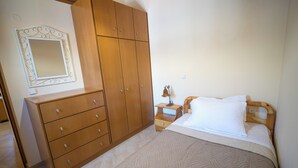 Un dormitorio con cama, armario de madera y mesita de noche con lámpara.