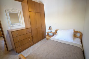 Ein Schlafzimmer mit einem Bett, einem Holzschrank und einem Nachttisch mit Lampe.