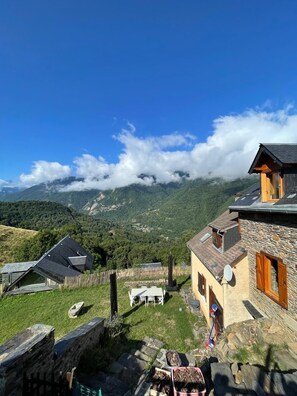 A mountain village with traditional stone houses, a wooden fence, and a clear view of the surrounding hills and mountains. - Charming Mountain Cabin (Baren)