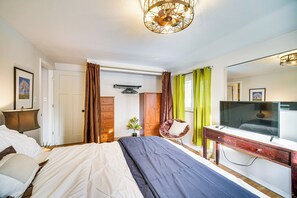 Une chambre à coucher avec un lit, un bureau, une chaise, une télévision et un miroir.