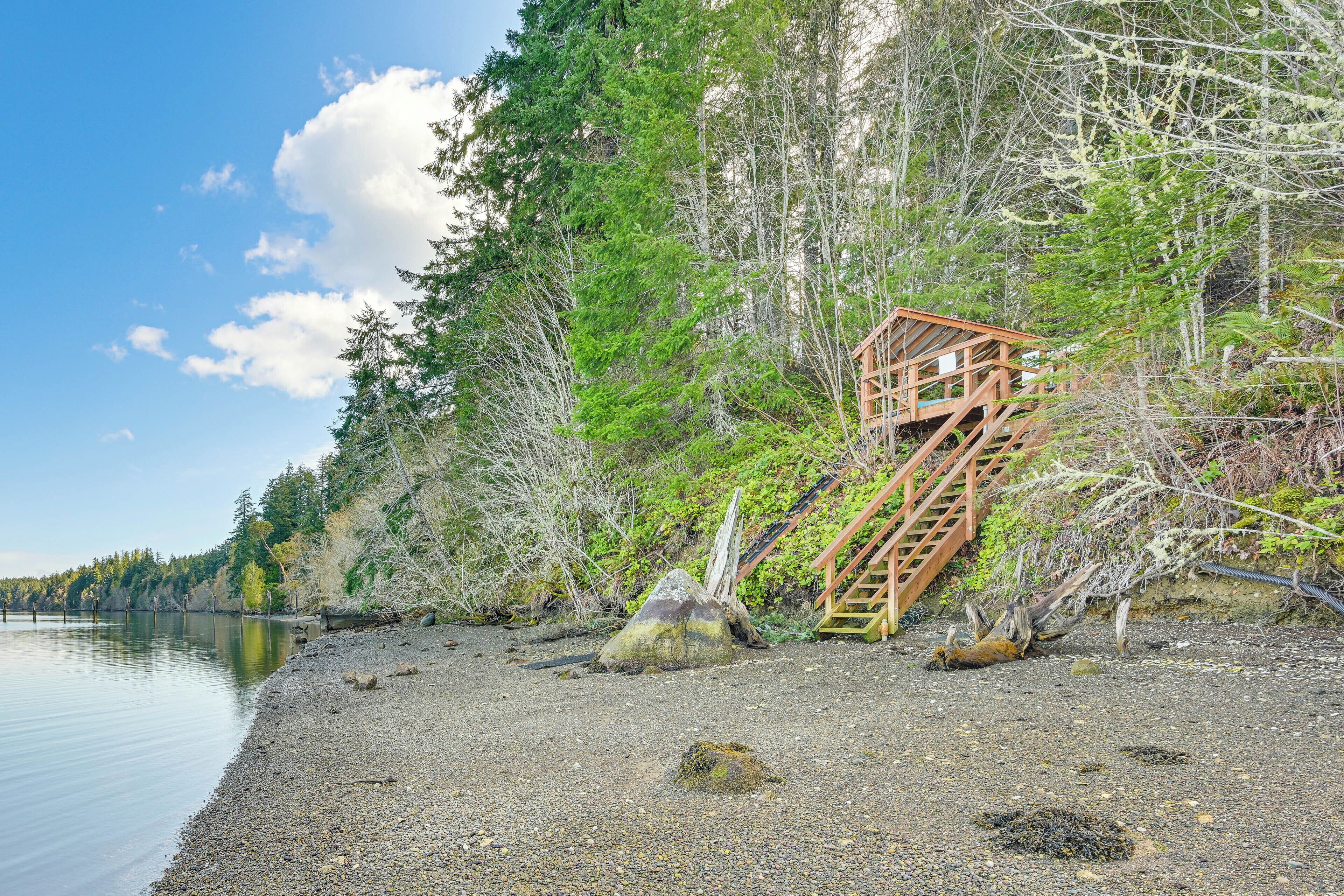 A wooden staircase leading up a rocky shore, surrounded by dense trees and a calm lake.