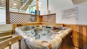 A spa area with a hot tub, wooden flooring, and a sign listing SPA WARNINGS. - Fully Renovated! Luxe Ski Condo Near Stowe Mtn (Stowe)