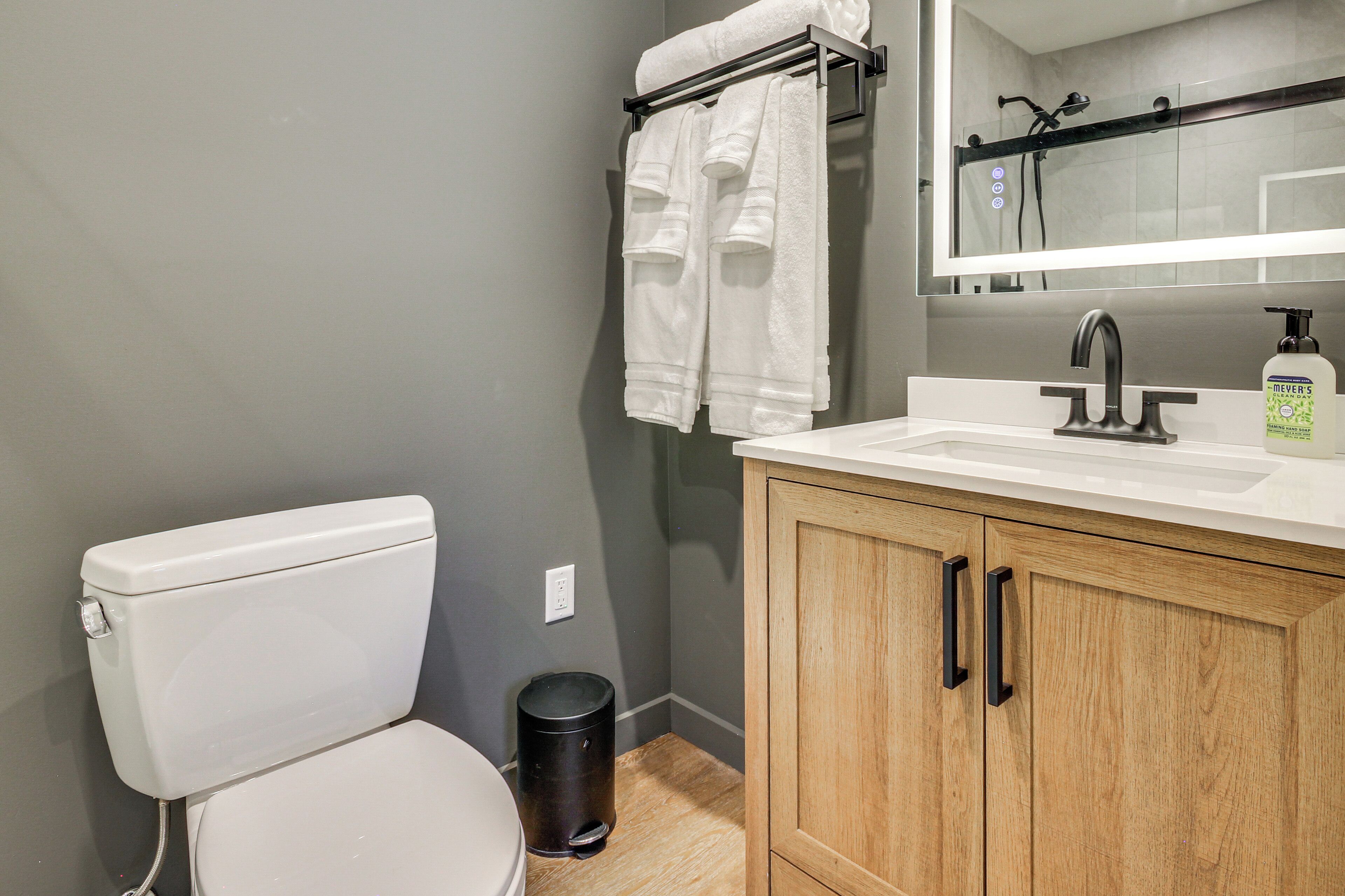 A bathroom with a toilet, a sink, a mirror, and a cabinet.