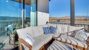 A modern living room with a sectional sofa, large windows, and a view of a train track.