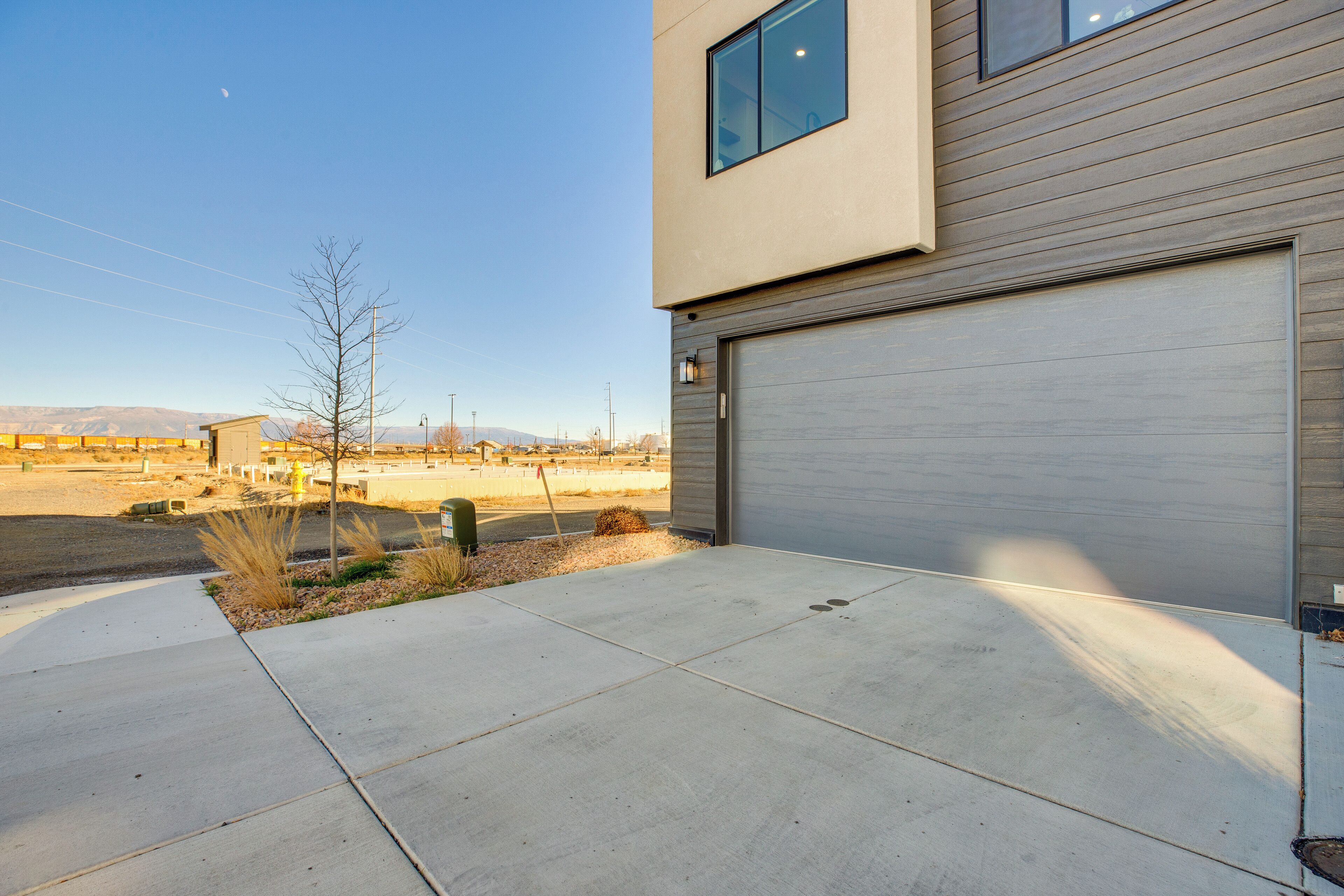 A modern building with a garage door, a clear sky, and a parking lot.