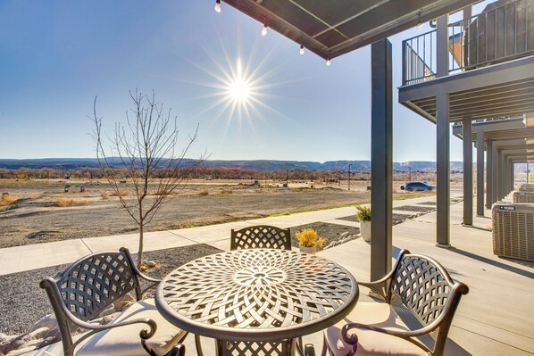 A patio with a round table and chairs, a covered area, and a view of a desert landscape.