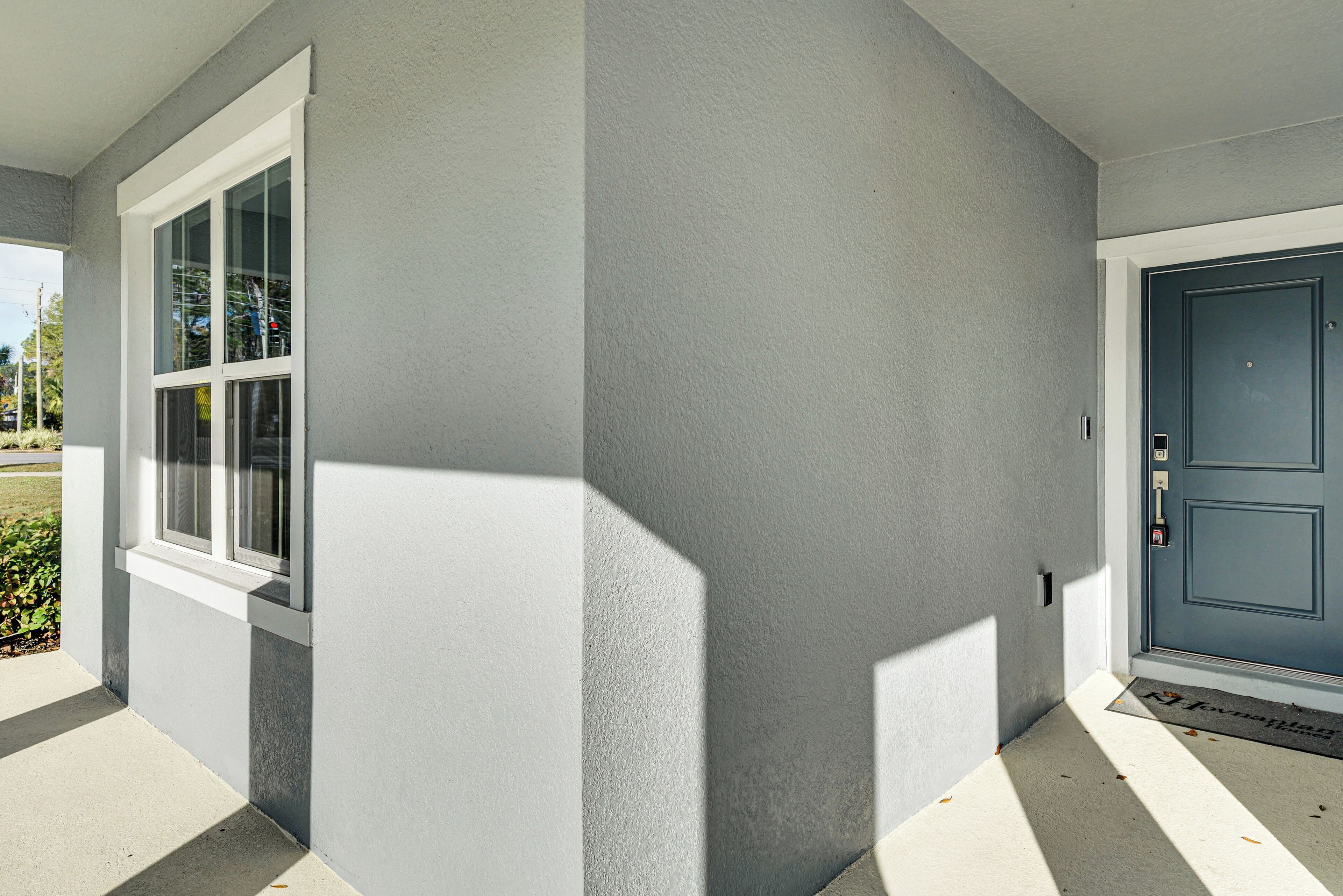 Een huis met een witte raam, een blauwe deur en een betonnen veranda.