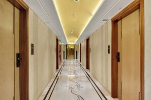 A hotel corridor with a marble floor, wooden doors, and a modern ceiling design. - Nanak Niwas Beacon New Delhi Paharganj (New Delhi)