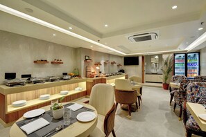 Ein Speisebereich eines Hotels mit Buffet, Sitzgelegenheiten und einem Fernseher.