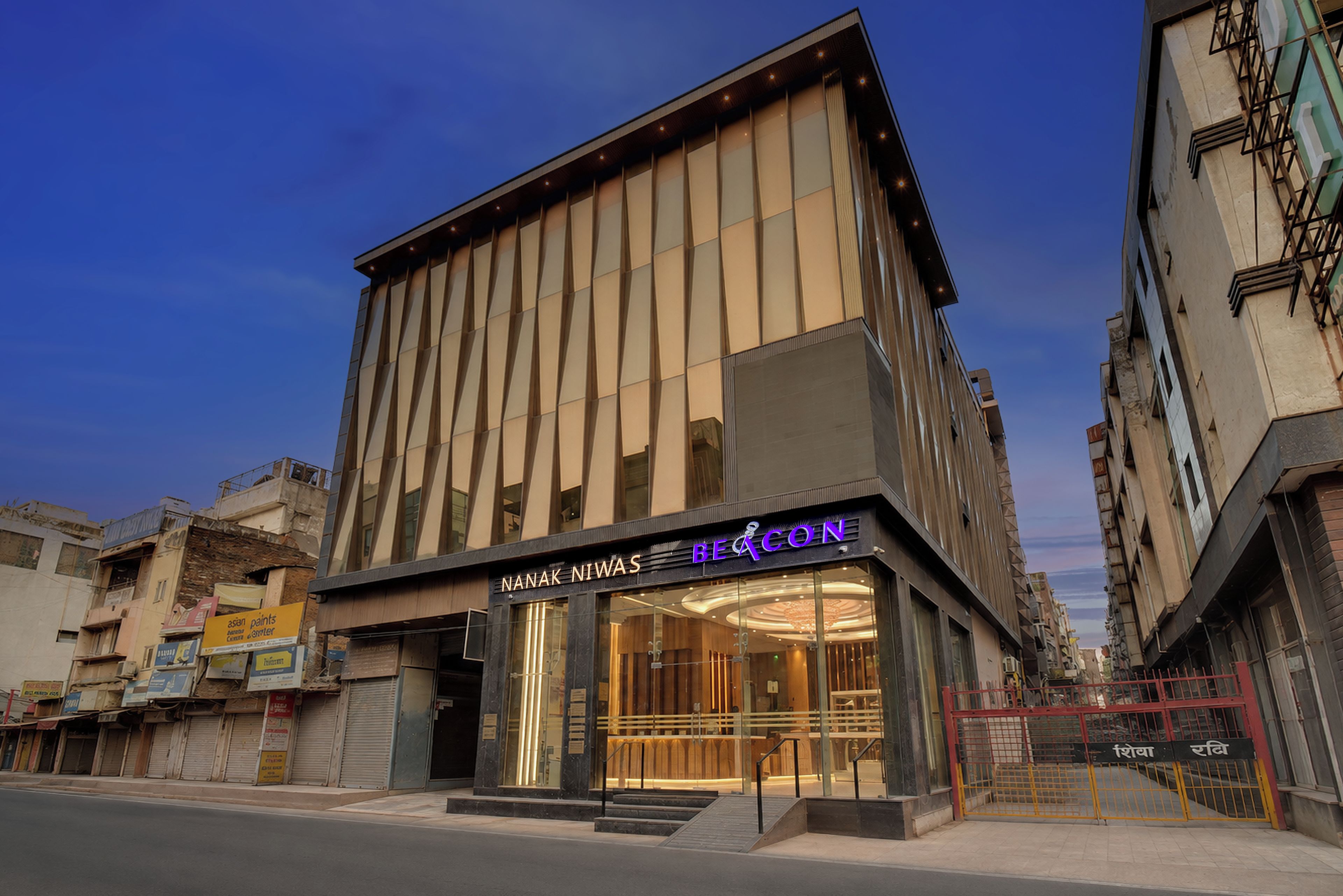 A modern building with a glass entrance and signage for 'Nanak Niwas' and 'Beacon.'