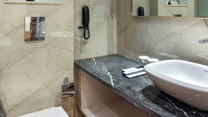 Une salle de bain moderne avec un sol en marbre, un grand miroir, un lavabo blanc et des toilettes.
