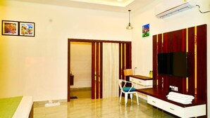 A hotel room with a bed, a desk with a chair, a TV, and a wardrobe. - Karhandla Tigers Farm And Resort (Umred)