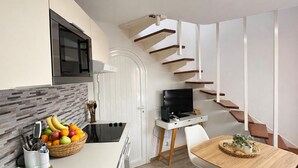 Eine moderne Küche mit Einbauherd, eine Essecke mit Holztisch und eine Treppe mit Holzboden.