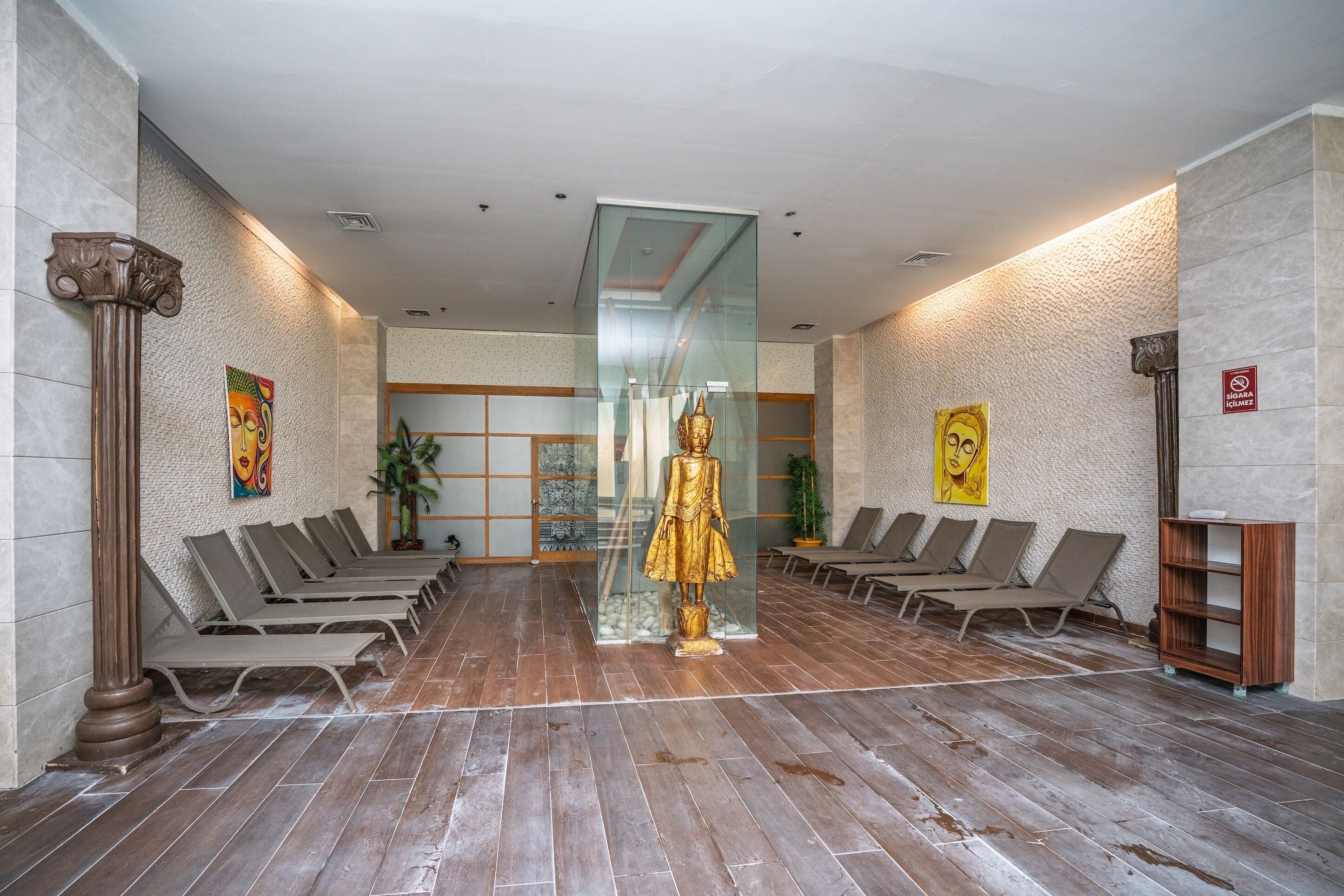 Eine Lobby mit einer zentralen Glaswand, Reihen von Loungesesseln und einer goldenen Statue.