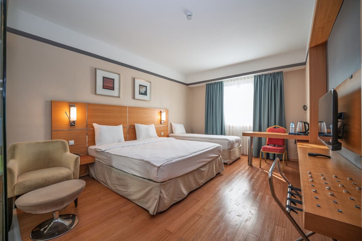 Una habitación de hotel con dos camas, un escritorio, una silla y un televisor.