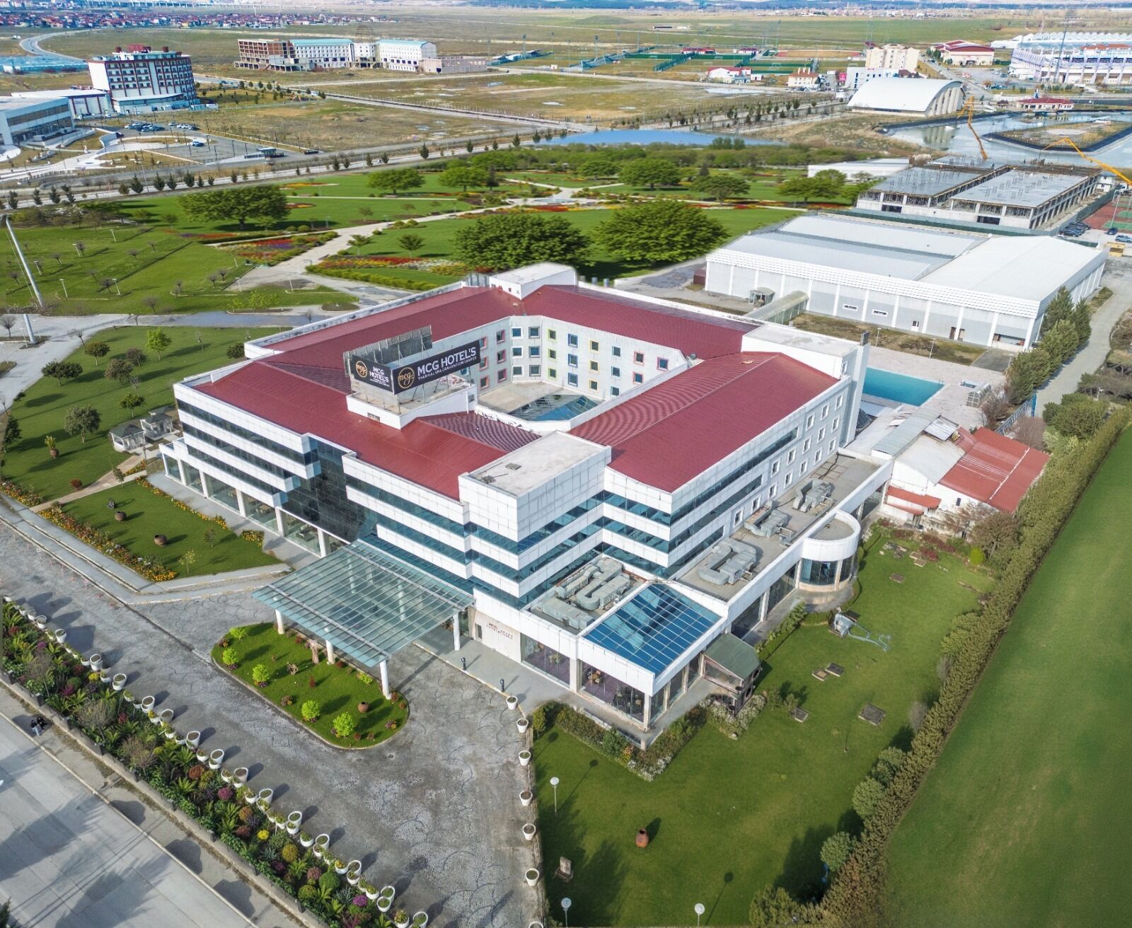 A modern hotel with a central courtyard, multiple floors, and a red roof.