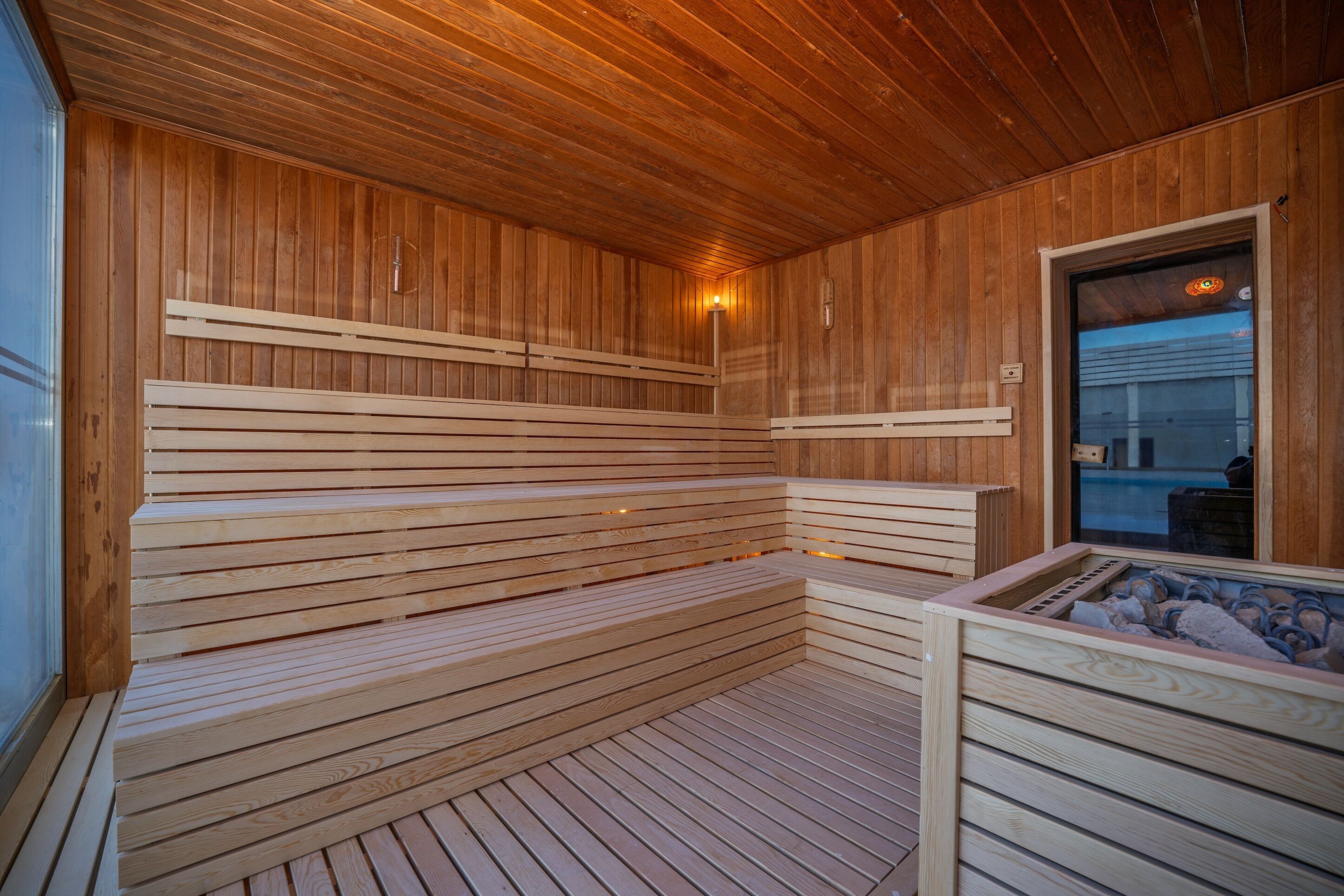A wooden sauna with benches and a stone basin.