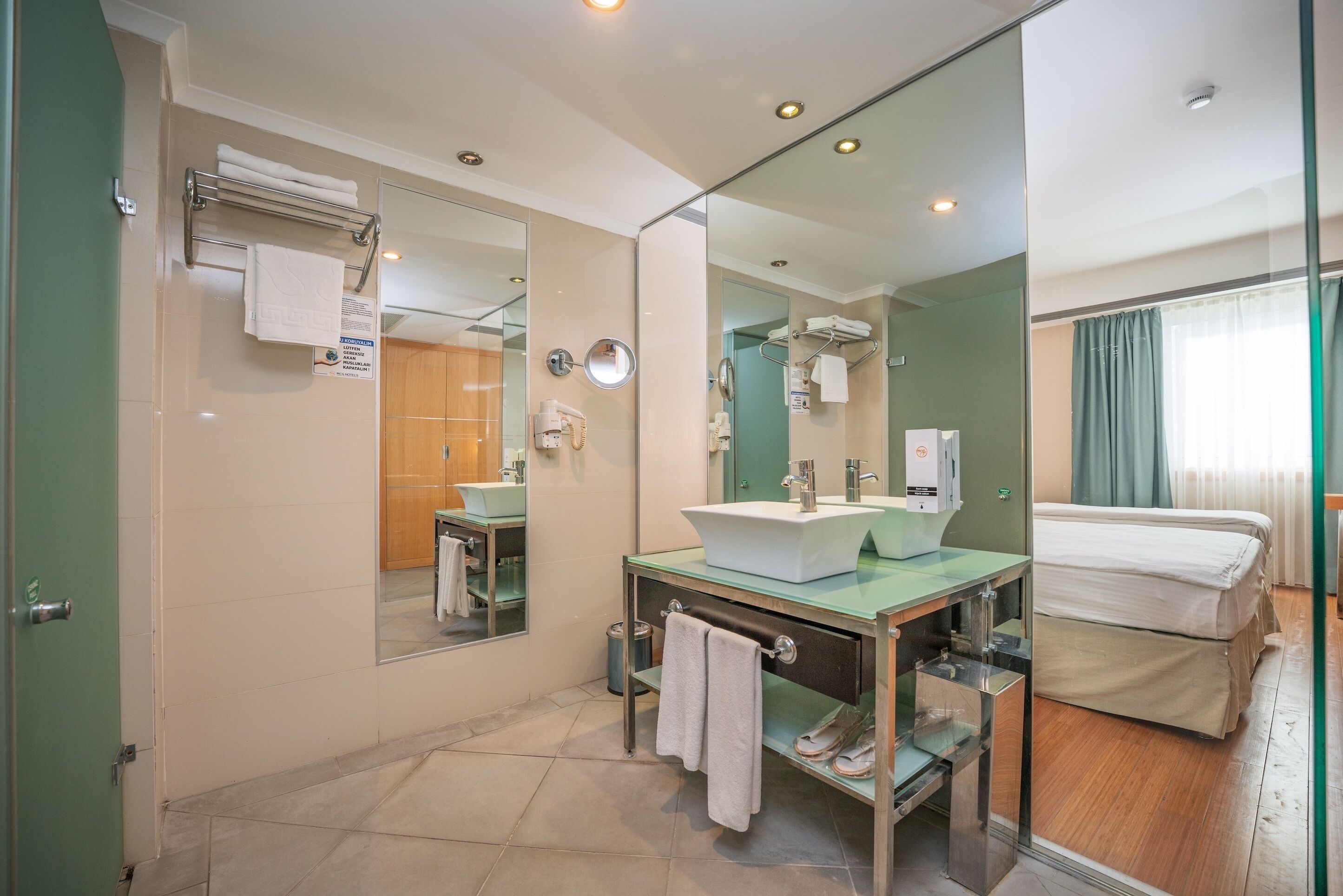 A modern bathroom with a glass vanity, a large mirror, and a shower area.